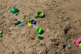 Children's toys are scattered on the sandy beach.
