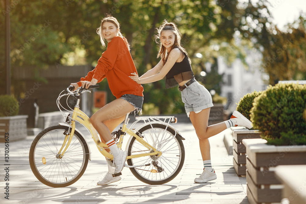 Portrait of beautiful girlfriends. Model in summer city. Girlfriends with bocycle.