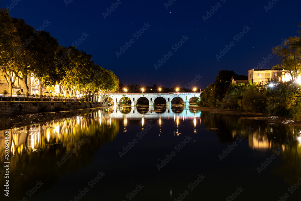 Vue nocturne sur le Pont Tibère et sa réflexion sur les eaux du fleuve Vidourle à Sommières (Occitanie, France) Vue nocturne sur le Pont Tibère et sa réflexion sur les eaux du fleuve Vidourle à Sommières (Occitanie, France)