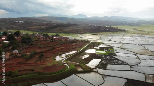 Stunning view of a beautiful rice paddy field near Antsirabe surrounded by a traditional village and valley in the background, during rainy season, famous travel destination in Madagascar 