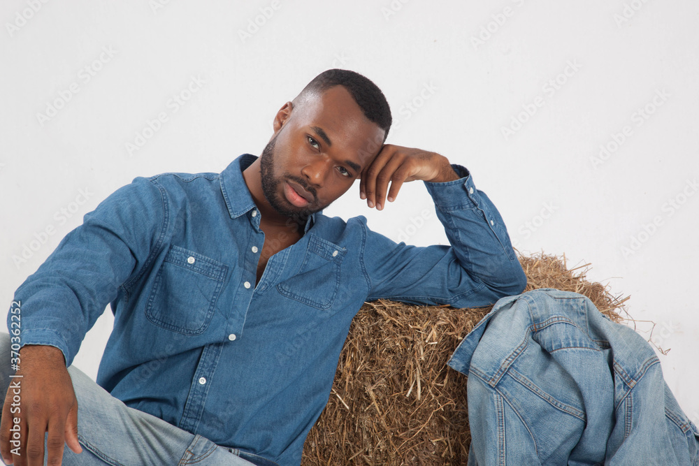 Handsome black man sitting with a bale of hay Handsome black man sitting with a bale of hay