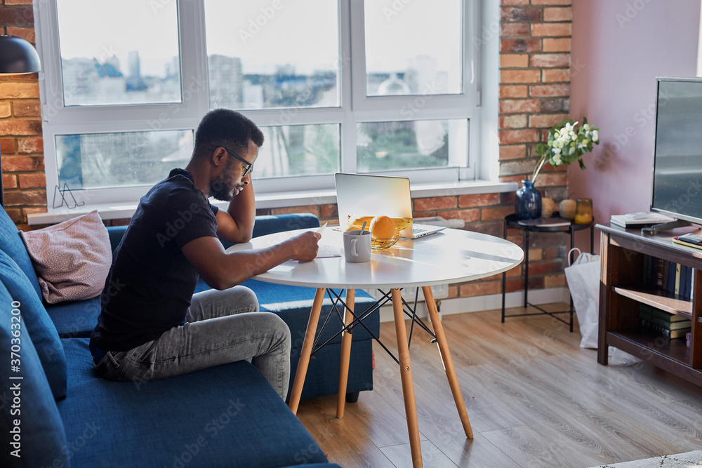 portrait of young african man concentrated on work at home, hardworkng guy sit reading document, he is on freelance, in the morning portrait of young african man concentrated on work at home, hardworkng guy sit reading document, he is on freelance, in the morning