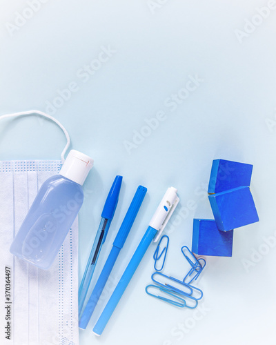 Education or back to school concept. Blue school supplies and medical face mask. New normal during coronavirus pandemic. Virus protection, keep distance. Copy space for text