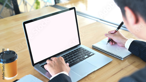 Businessman is using a computer laptop and taking at the wooden working table.