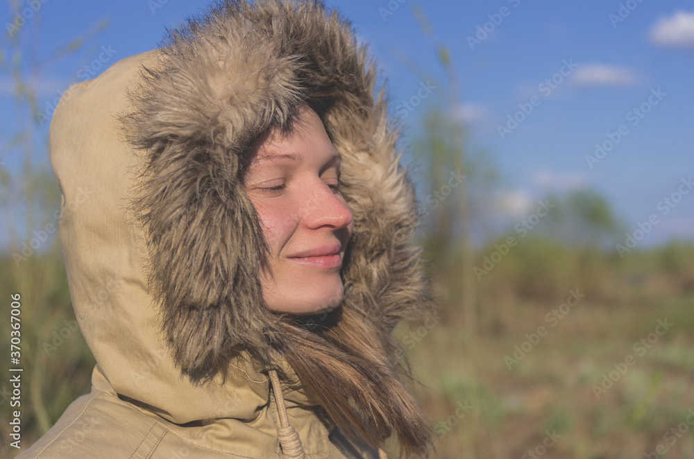 A woman in a jacket and hood looks at the river A woman in a jacket and hood looks at the river