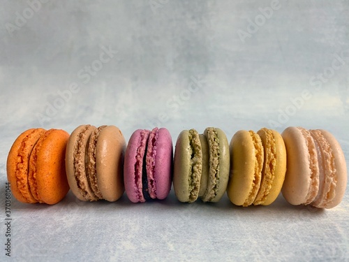 Colorful macarons in a row on a white /gray background