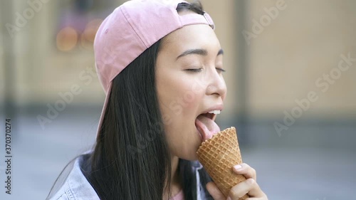 Close up portrait of cute asian woman licking and eating icecream. Slowmotion.
