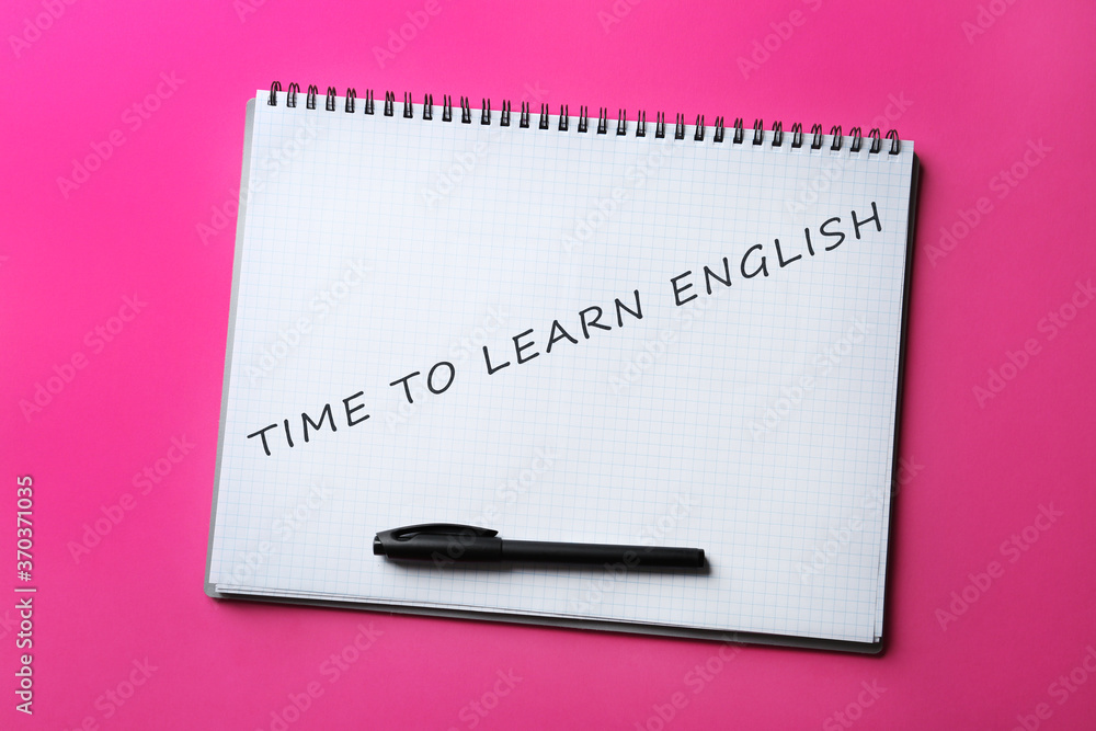 Open notebook with text Time To Learn English and pen on pink background, top view Open notebook with text Time To Learn English and pen on pink background, top view