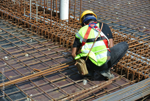 MALACCA, MALAYSIA -MAY 27, 2016: Construction workers fabricating steel reinforcement bar at the construction site in Malacca, Malaysia. The reinforcement bar was ties together using tiny wire. 