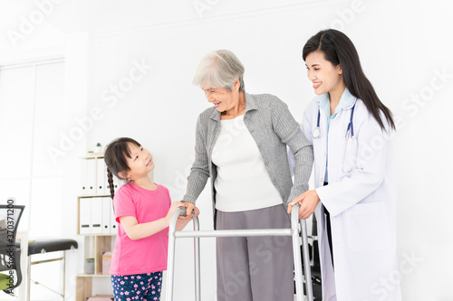 close up old woman, walk training and rehabilitation process, old asian stroke patient learning to uses walker with female doctor and her family in hospital, elderly healthcare promotion