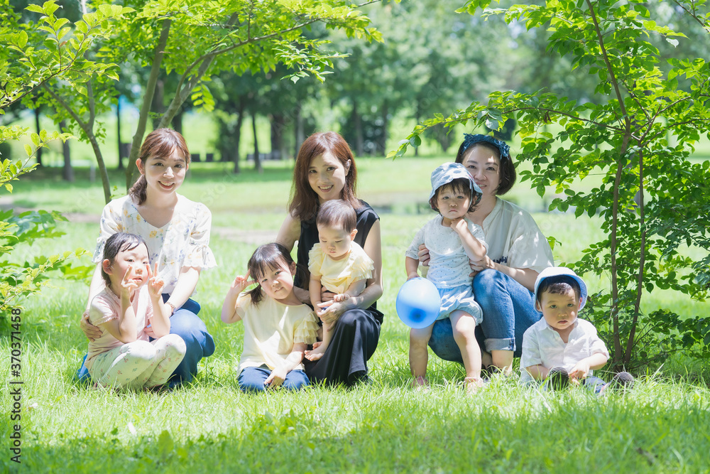 Fototapeta premium 緑あふれる公園で遊ぶ家族たちの集合写真
