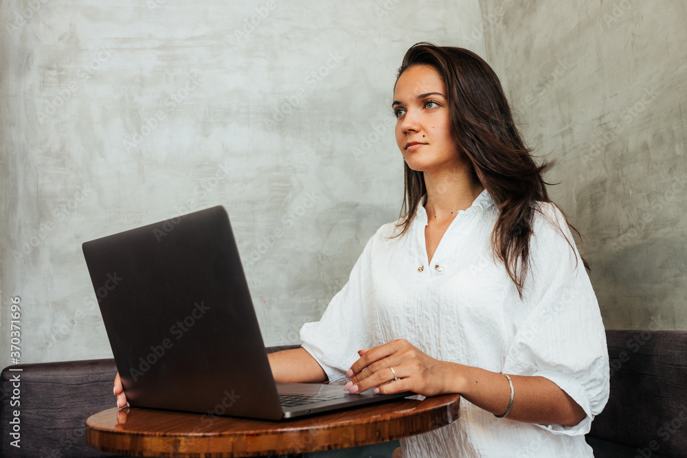 Young pretty girl works for her laptop while sitting in a cafe. Business lady not in office Young pretty girl works for her laptop while sitting in a cafe. Business lady not in office