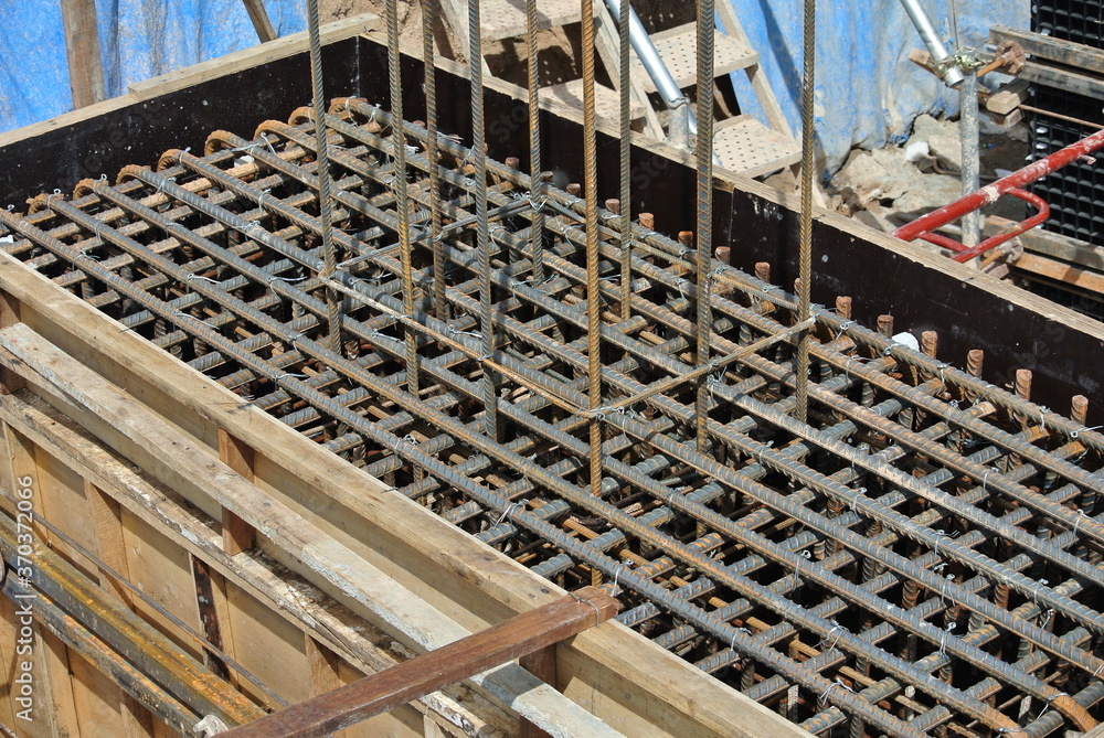 KUALA LUMPUR, MALAYSIA -JULY 16, 2019: Construction workers fabricating steel reinforcement bar inside the timber formwork at the construction site. It was a must process before pouring the concrete. 