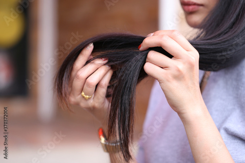 Woman hand holding her long hair with looking at damaged splitting ends of hair care problems