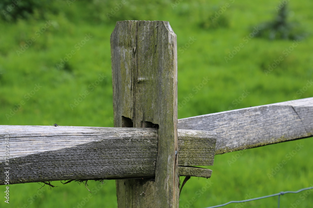 A closeup view of a traditional old English wooden post and rail farm fence.