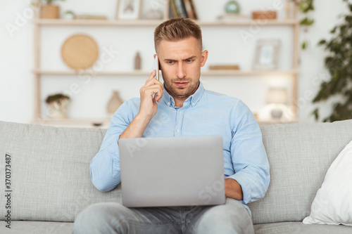 Portrait of successful businessman using phone and pc