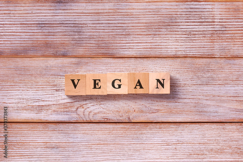 Word Vegan written on cubes on white wooden background. Healthy vegan food diet concept.