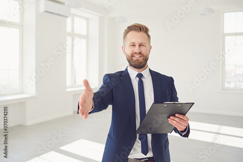 Male real estate agent with handshake smiling in white real estate room apartment home