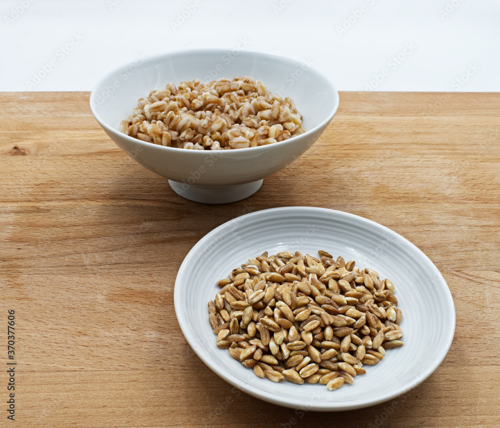 Boiled spelt in a bowl isolated on wooden background with seeds Boiled spelt in a bowl isolated on wooden background with seeds