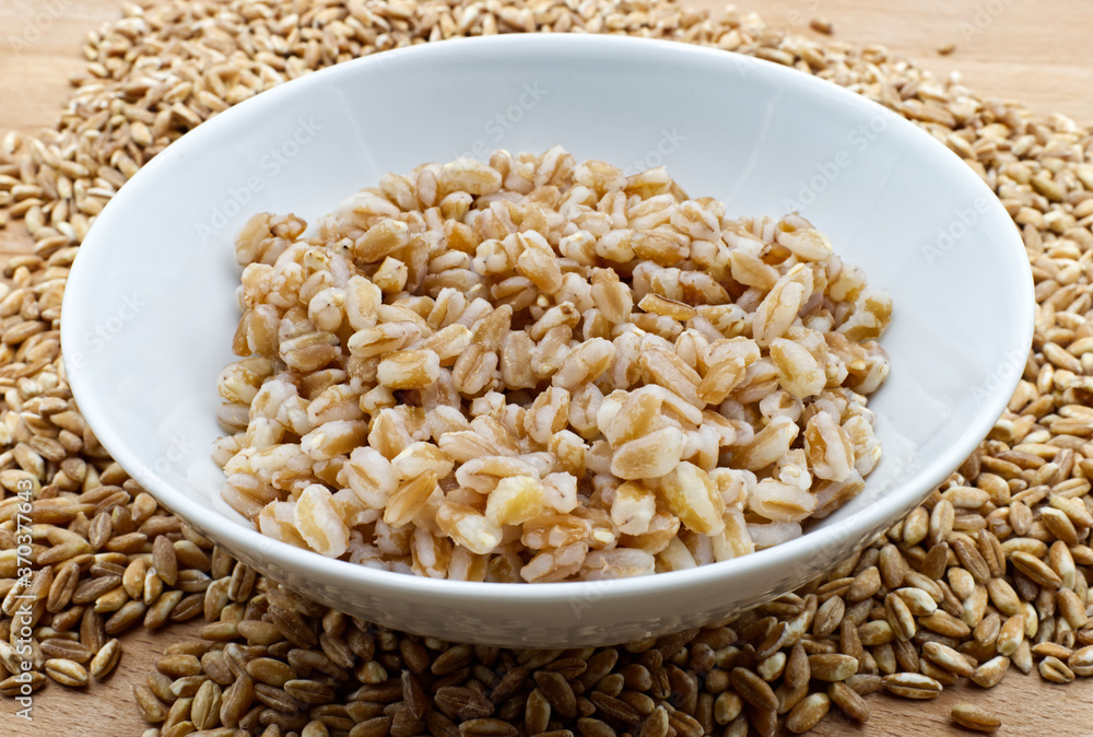Boiled spelt in a bowl isolated on wooden background with seeds Boiled spelt in a bowl isolated on wooden background with seeds