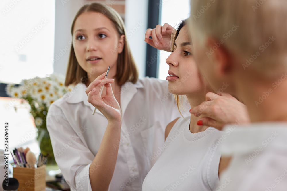 process of making makeup in beauty salon. visagiste working with brush on model face. applying tone to skin. professional make-up artist paints model process of making makeup in beauty salon. visagiste working with brush on model face. applying tone to skin. professional make-up artist paints model