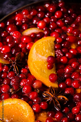 metal pot on the stove. Oranges and cranberries in mulled wine