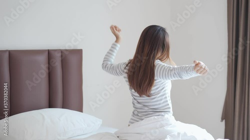 Wallpaper Mural Young asian woman sitting on the bed and stretch oneself in the morning Torontodigital.ca