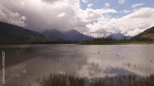 Wallpaper Mural Drone Glide Forward Over Tall Reedy Marshland and Out Over the Water as a Dark Mountain Looms in the Distance Gathering Clouds and Turning a Blue Sky Grey Torontodigital.ca