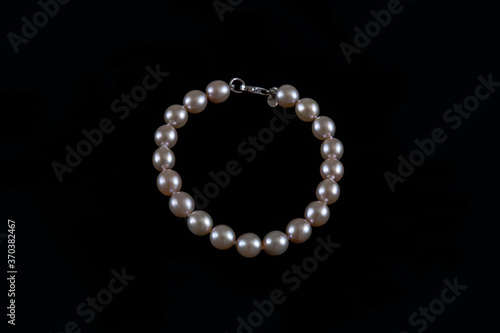 Genuine round pearls bracelet in ivory color against a black background, elegant precious organic jewelry worn as accessory for a formal or a casual-chic attire or as birthstone for the month of June