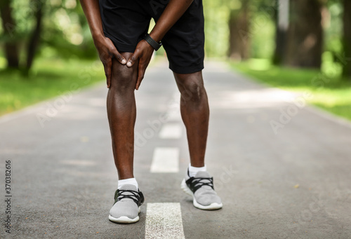 Closeup of black sportsman rubbing his sore knee