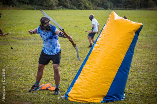 Teenage boy playing archery tag on a meadow