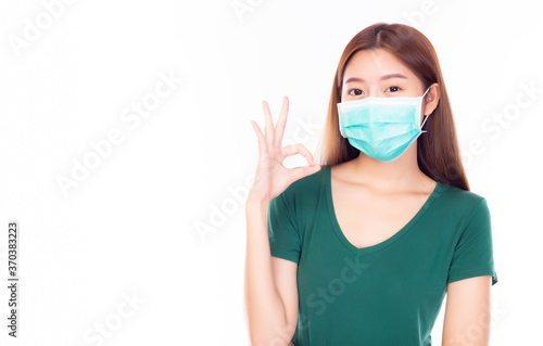 Young asian woman wear medical mask for protection versus viruses and infection or protection of air pollution. She give okay sign for telling she get safe. Prevention and protection covid 19 concept