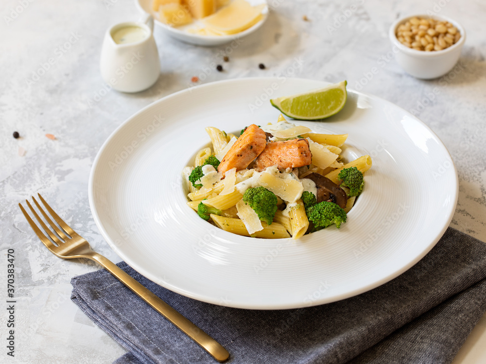 Pasta penne with salmon, broccoli, and pesto sauce on the white-gray background. Flat lay.