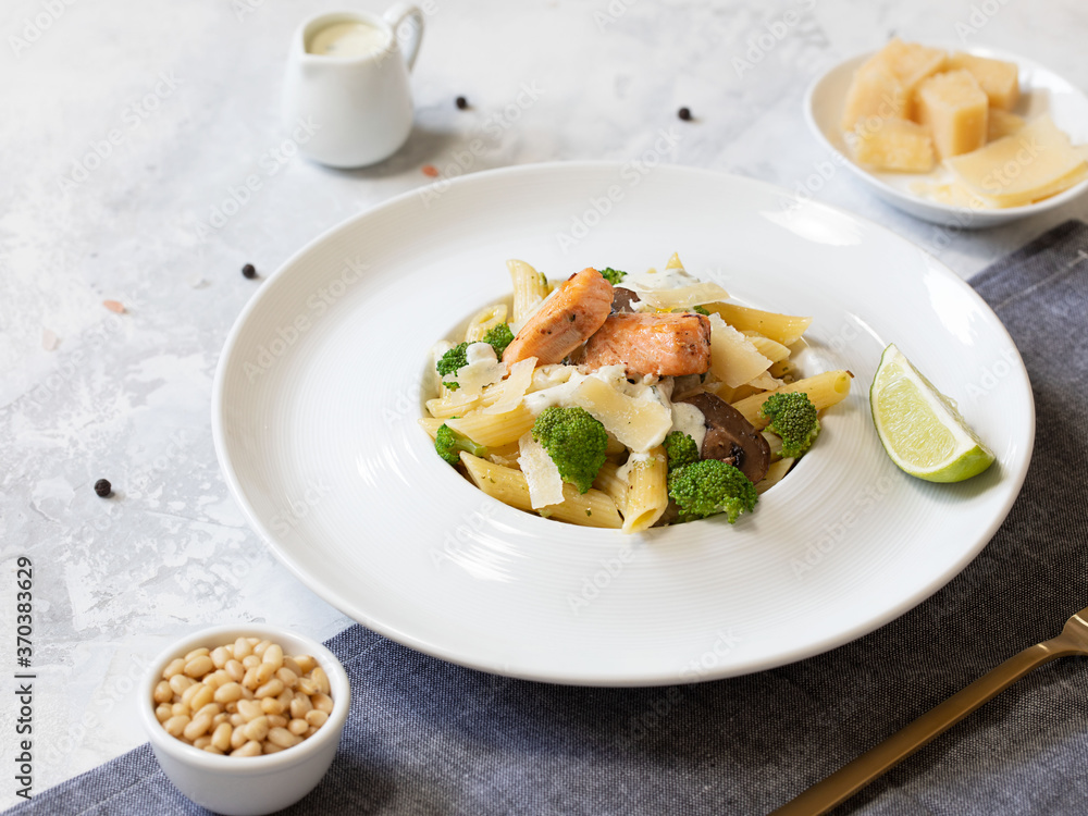 Pasta penne with salmon, broccoli, and pesto sauce on the white-gray background. Flat lay. Pasta penne with salmon, broccoli, and pesto sauce on the white-gray background. Flat lay.