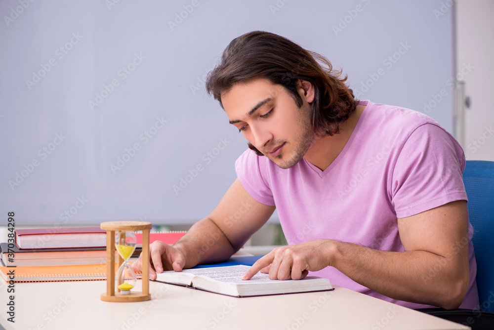 Young male student in the classroom at time management concept Young male student in the classroom at time management concept