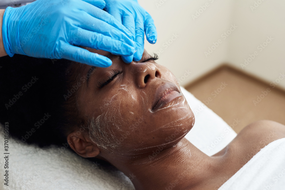 A beautiful young woman enjoys a toning facial massage. The concept of spa treatments, skin care and anti-aging A beautiful young woman enjoys a toning facial massage. The concept of spa treatments, skin care and anti-aging