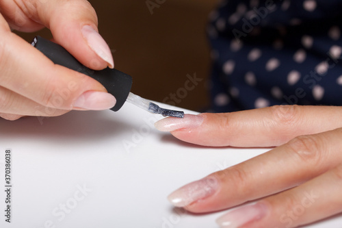 A woman gives herself a manicure. Apply new nail Polish with a brush. Taken in close-up.