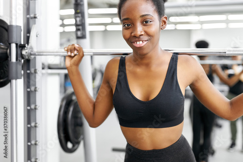 athletic african woman pumping up muscles with barbell, crossfit weightlifting or deadlifting workout training in the gym