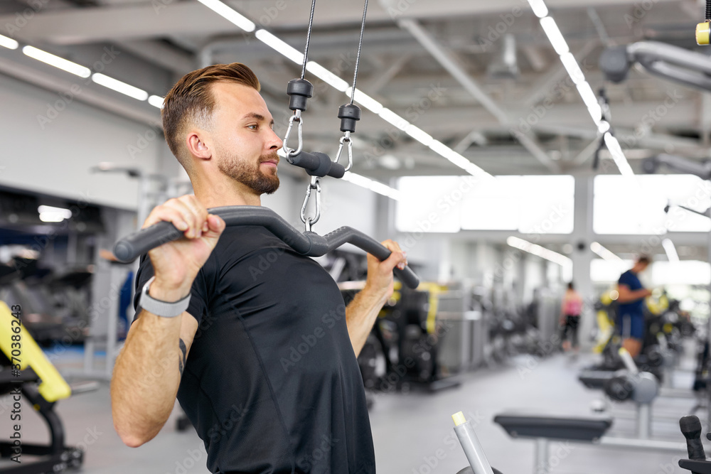young caucasian man trains on fitness equipment in the gym, pumps arms muscles, healthy lifestyle young caucasian man trains on fitness equipment in the gym, pumps arms muscles, healthy lifestyle