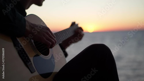 Playing guitar at sunrise, seaside