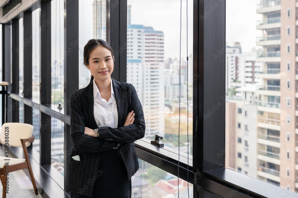 Young asian businesswoman standing crossed arm in modern office