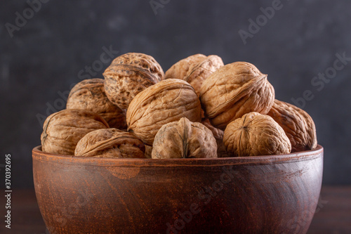 Walnut in a clay bowl close-up against a dark background