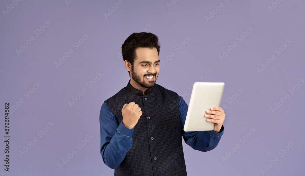 Young Indian guy with tablet computer gesturing YES on violet background Young Indian guy with tablet computer gesturing YES on violet background