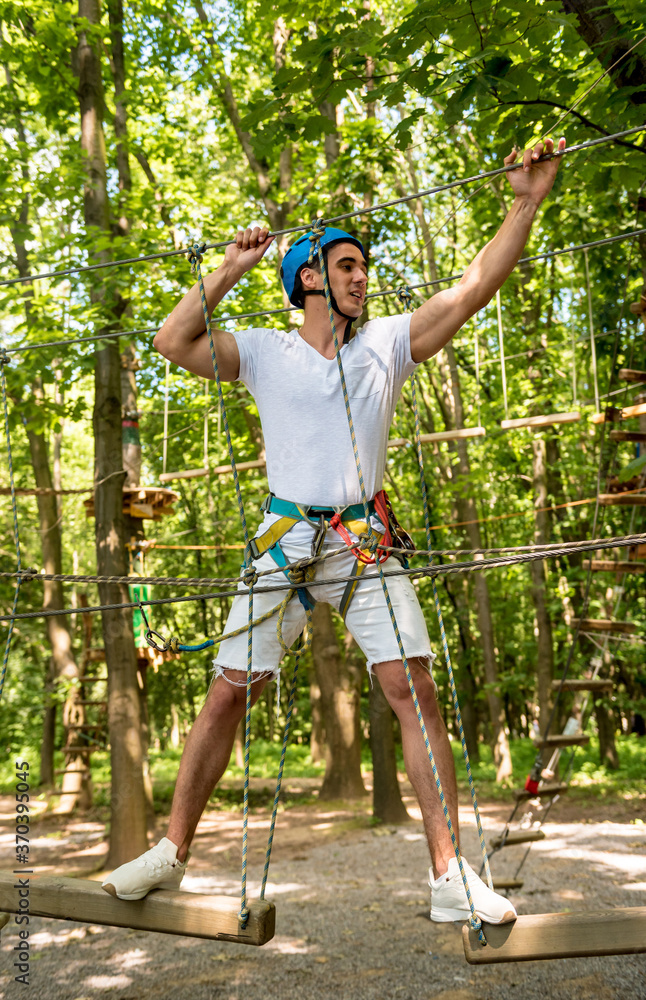 Fototapeta premium Young man in adventure rope park. Climbing Equipment.