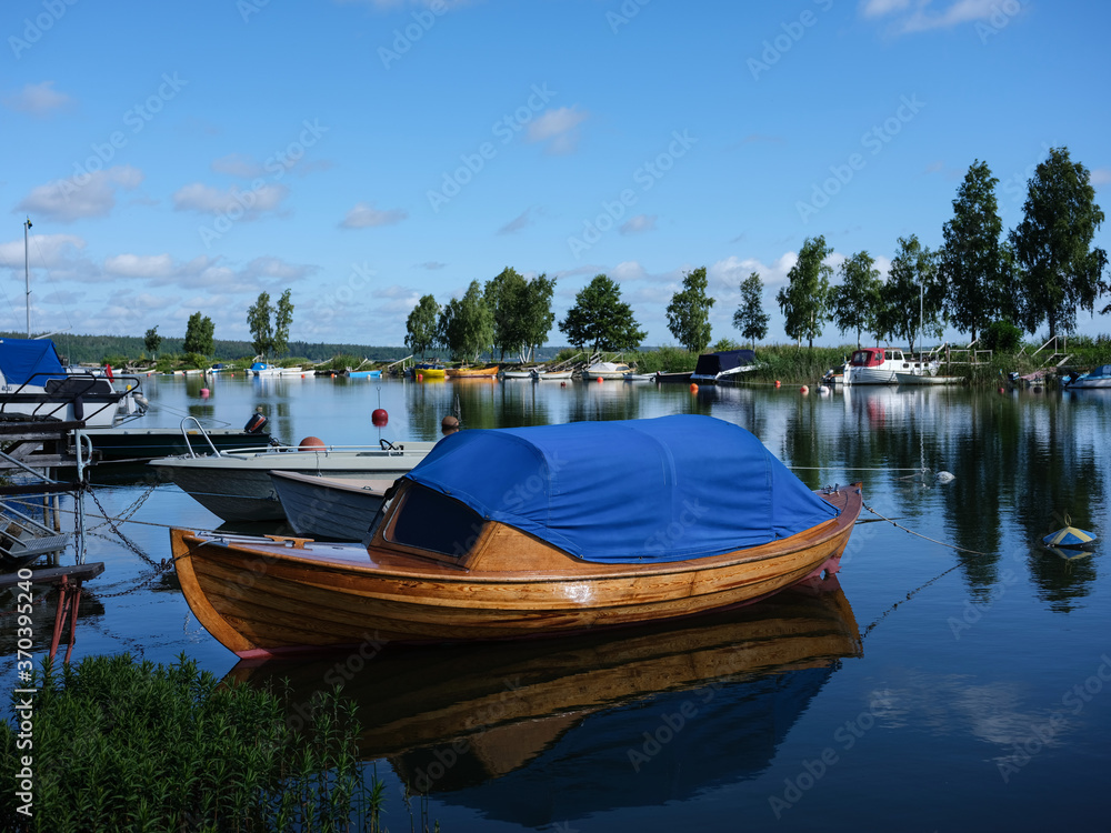 A beautiful wooden boat in a harbour in Sweden. The hull is varnished with the water reflecting. The photograph is shot with a medium format camera