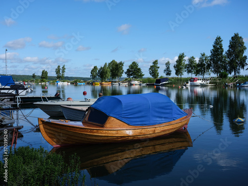 A beautiful wooden boat in a harbour in Sweden. The hull is varnished with the water reflecting. The photograph is shot with a medium format camera