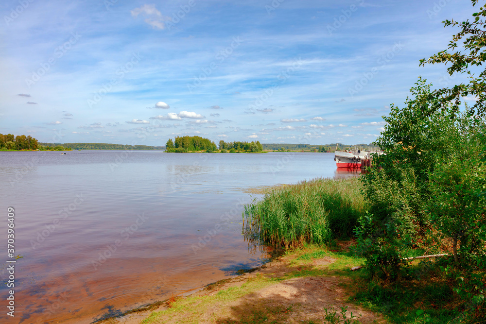 The Volga river near the city of Volgorechensk, Russia. The bank, overgrown with reeds, can be seen in the background of river ships.