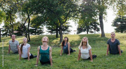 Fototapeta Naklejka Na Ścianę i Meble -  A group of people do yoga in the Park at sunset. Healthy lifestyle, meditation and Wellness
