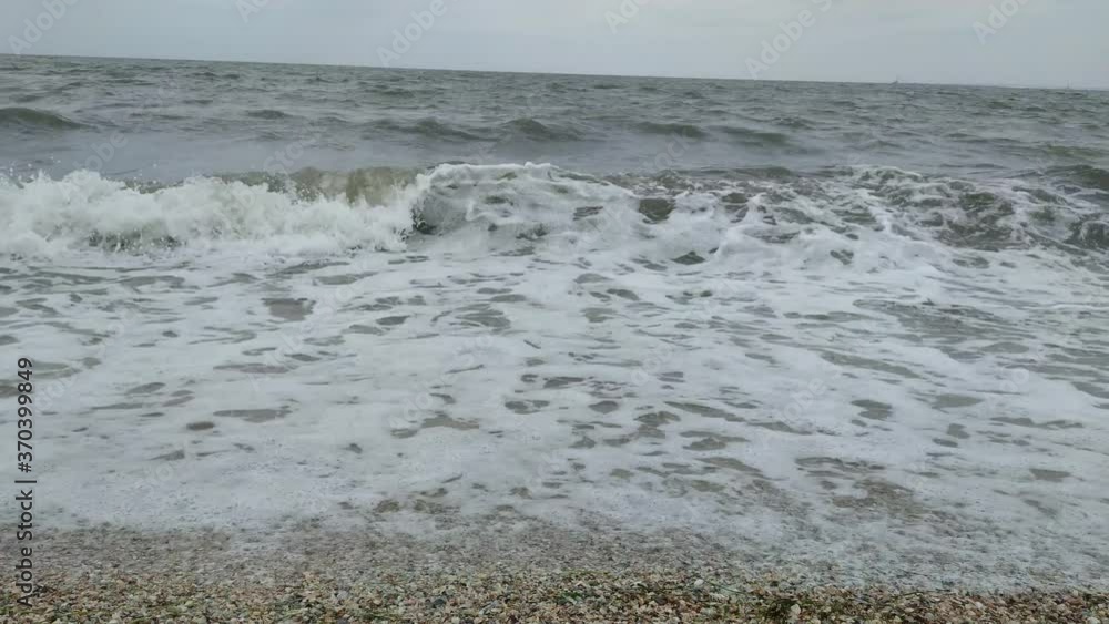 Storm at sea, high waves wash the sandy shore. Sea waves break on the shore and foam. View from the shore. Storm at sea, high waves wash the sandy shore. Sea waves break on the shore and foam. View from the shore.