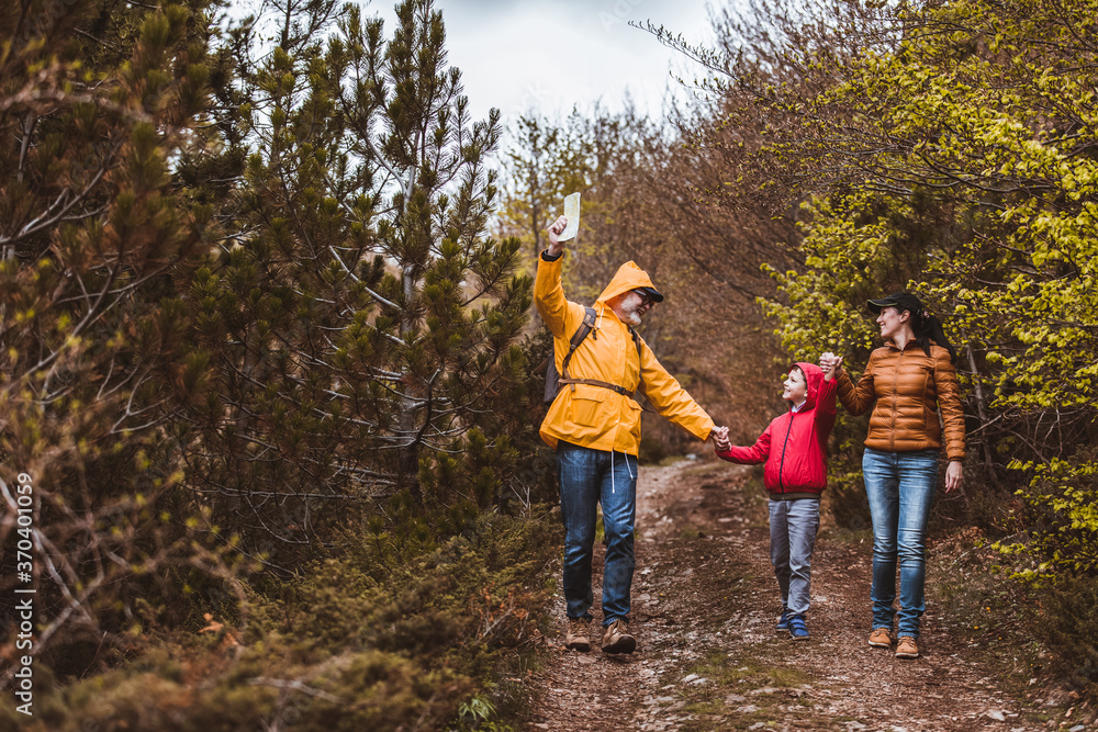 Happy family walking with backpacks in woods and having fun.